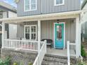 Inviting front porch with brick base, white railing, and a bright blue front door at 1006 Whistler St, Durham, NC 27713