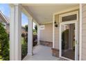 Inviting porch with stately columns, brick accents, and a view of landscaped greenery at 102 Mikaila Dr, Gibsonville, NC 27249