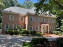 Charming two-story brick home with mature trees and manicured landscaping with a welcoming front entrance at 1105 Tazwell Pl, Raleigh, NC 27612