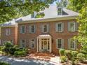 Elegant brick home with dormer windows, gray shutters, and a covered entrance exudes timeless charm and sophistication at 1105 Tazwell Pl, Raleigh, NC 27612