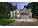Inviting two-story home with a brick and siding exterior, solar panels, and attached two-car garage during dusk at 1205 Magnolia Hill Rd, Garner, NC 27529