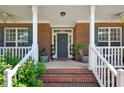 Inviting brick front porch with white railings, potted plants, and a stylish front door at 1205 Magnolia Hill Rd, Garner, NC 27529
