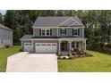 Beautiful two-story gray home with a three-car garage, covered front porch, and well-manicured lawn at 165 Hickory Grv Dr, Sanford, NC 27330