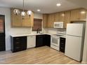 Bright kitchen with white appliances, wooden cabinets, black hardware, and hardwood floors at 205 Woodhaven Dr, Burlington, NC 27217