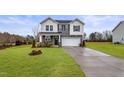Charming two-story home with gray and white siding, a two-car garage, and a manicured lawn at 21 Whistling Way # 17, Lillington, NC 27546