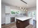 Updated kitchen with stainless dishwasher, modern lighting, and backyard view at 2725 Gross Ave, Wake Forest, NC 27587