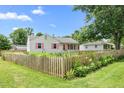 View of the cute white home with a pretty wooden fence and green, landscaped front yard at 302 Bradley St, Burlington, NC 27215