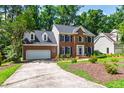View of a brick home featuring a two-car garage and driveway with mature landscaping at 4309 Omni Pl, Raleigh, NC 27613