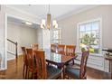Elegant dining room featuring a large wooden table, chandelier lighting, and ample natural light from the windows at 437 Excalibur Dr, Morrisville, NC 27560