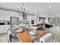 Open dining area with a modern chandelier, a dining table set for a meal, and a view of the kitchen at 5032 Jowetts Walk Dr # 26, Cary, NC 27519