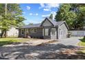 Single-story home with a gray exterior, gravel driveway, and manicured front lawn on a sunny day at 506 W Walnut St, Selma, NC 27576