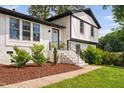 Beautiful white brick house with manicured front yard, featuring brick steps, black railings, and tasteful landscaping at 5400 Kaplan Dr, Raleigh, NC 27606