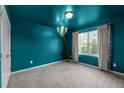 Empty blue bedroom with a chandelier, tan curtains, and large window at 7 Faircroft Ct, Durham, NC 27703