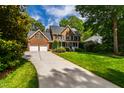 Elegant brick home boasting a spacious driveway, manicured lawn, and mature trees at 7620 Rainwater Rd, Raleigh, NC 27615