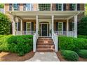 Inviting front porch with brick steps, white railings, and well-manicured shrubs at 7620 Rainwater Rd, Raleigh, NC 27615