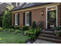 Close-up of a brick home's entrance, featuring a dark front door, black shutters, and manicured landscaping at 815 Marlowe Rd # 10, Raleigh, NC 27609