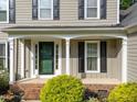 Close up of front door and porch with brick foundation and green shrubbery at 120 E Laurenbrook Ct, Cary, NC 27518