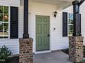 Close-up of a charming home entrance featuring an olive-green front door with brick pillars at 157 E Wilson St, Clayton, NC 27520
