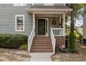 Inviting covered front porch with brick stairs, a flower basket, and a view of the landscaped front yard at 1815 Crystal Downs Lane, Raleigh, NC 27604
