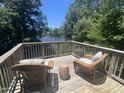 Relaxing deck with wicker furniture, offering beautiful lake views and surrounded by lush trees at 2053 Thornblade Dr, Raleigh, NC 27604
