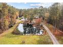 Aerial view of private pond, surrounded by mature trees, and charming home at 3564 Lower Moncure Rd, Sanford, NC 27330