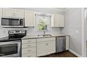 Well-lit kitchen features stainless appliances, white cabinets, a double sink, and a subway tile backsplash at 405 E Millbrook Rd, Raleigh, NC 27609
