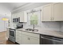 Bright kitchen features stainless appliances, gray counters, white cabinets, subway tile backsplash, and a double sink at 405 E Millbrook Rd, Raleigh, NC 27609