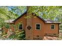 Side exterior of the home featuring wood siding, a brick chimney, and well-maintained landscaping at 5315 Mccormick Rd, Durham, NC 27713