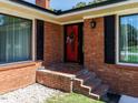 Close up of brick front porch, a red front door decorated with a wreath and black shutters at 712 E Horne St, Clayton, NC 27520
