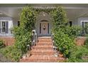 Inviting front porch with brick steps, lush greenery, and decorative lanterns at 7917 Rooksley Ct, Raleigh, NC 27615