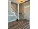 Inviting foyer with wood-look flooring, staircase with wood banister, and natural light streaming through the front door at 8100 Laurel Mountain Rd, Raleigh, NC 27613