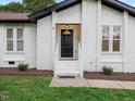 Close-up of the home's entrance, featuring a black door and well-maintained landscaping at 1709 Hawthorne Lane Ln, Burlington, NC 27215
