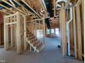 Wooden staircase in an unfinished home with exposed beams and door to the outside at 1808 Falls Landing Dr, Raleigh, NC 27614