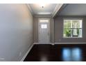Bright foyer featuring dark hardwood floors, crown molding, a window, and a white front door at 2008 Campana Dr, Raleigh, NC 27603