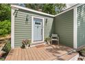 Cozy entryway with light gray front door, wood porch, potted flowers, and charming exterior lights at 2410 Huron St, Durham, NC 27707