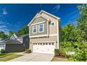 Front view of a two story home with a two car garage and a mix of siding and shingles, nestled between mature trees at 304 Garden Walk Dr, Durham, NC 27703