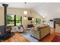 Bright living room with hardwood floors, wood burning stove, and large windows at 3213 Mid Pines Rd, Raleigh, NC 27606