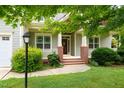 Inviting front porch with brick accents, classic columns, and verdant landscaping at 322 Bellemont Rd, Pittsboro, NC 27312