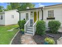 Charming cottage with a bright yellow front door and lush landscaping at 527 N Cypress St, Wendell, NC 27591