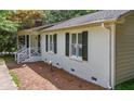 Brick home exterior shows side porch with white rails, trimmed windows with black shutters, and mature landscaping at 6501 Battleford Dr, Raleigh, NC 27613