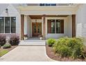 Inviting front porch featuring wood columns, a stylish door, and charming landscaping at 8420 Bells Lake Rd, Apex, NC 27539