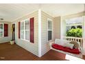 Relaxing porch view with a swing seat, red cushion, and peaceful outdoor ambiance at 86 Basswood Cir, Willow Springs, NC 27592