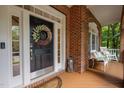 Inviting front porch area with decorative wreath on door and rocking chair seating at 100 Redfoot Run Rd, Chapel Hill, NC 27516