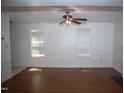 Bright living room features hardwood floors, a ceiling fan, and white walls with large windows allowing natural light at 103 Sara Dr, Nashville, NC 27856
