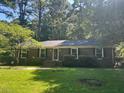 Brick home showcasing black shutters and a large front lawn surrounded by mature trees and lush greenery at 108 Shadowbrook Dr, Hillsborough, NC 27278