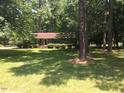 A quaint brick home is surrounded by mature trees and a lush green lawn, creating a serene and inviting atmosphere at 108 Shadowbrook Dr, Hillsborough, NC 27278