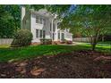 Two-story home featuring a manicured lawn, mature trees, and a partial view of the driveway at 12 Gatesway Ct, Durham, NC 27707