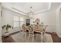 Elegant dining room featuring a decorative chandelier, a wooden table with seating for six, and wainscoting details at 175 Hawkesburg Dr, Clayton, NC 27527