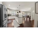 Open concept kitchen features white cabinets, an island with bar seating, and hardwood floors leading to a dining area at 175 Hawkesburg Dr, Clayton, NC 27527
