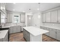 Light-filled kitchen showcasing gray cabinets, an island with seating, and stainless steel appliances at 1812 Gazania Dr, Fuquay Varina, NC 27526